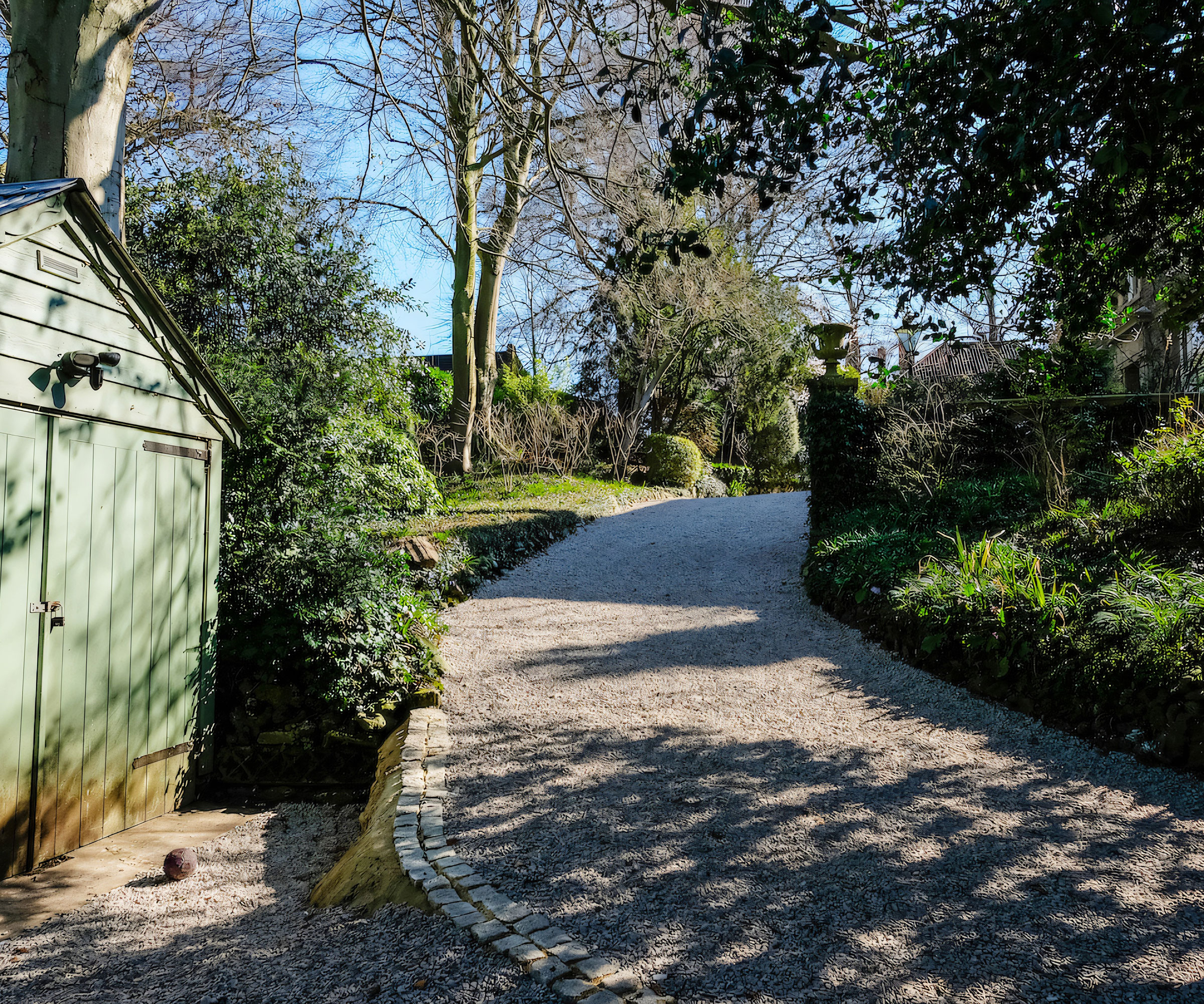 sloping gravel driveway with green shed at the bottom