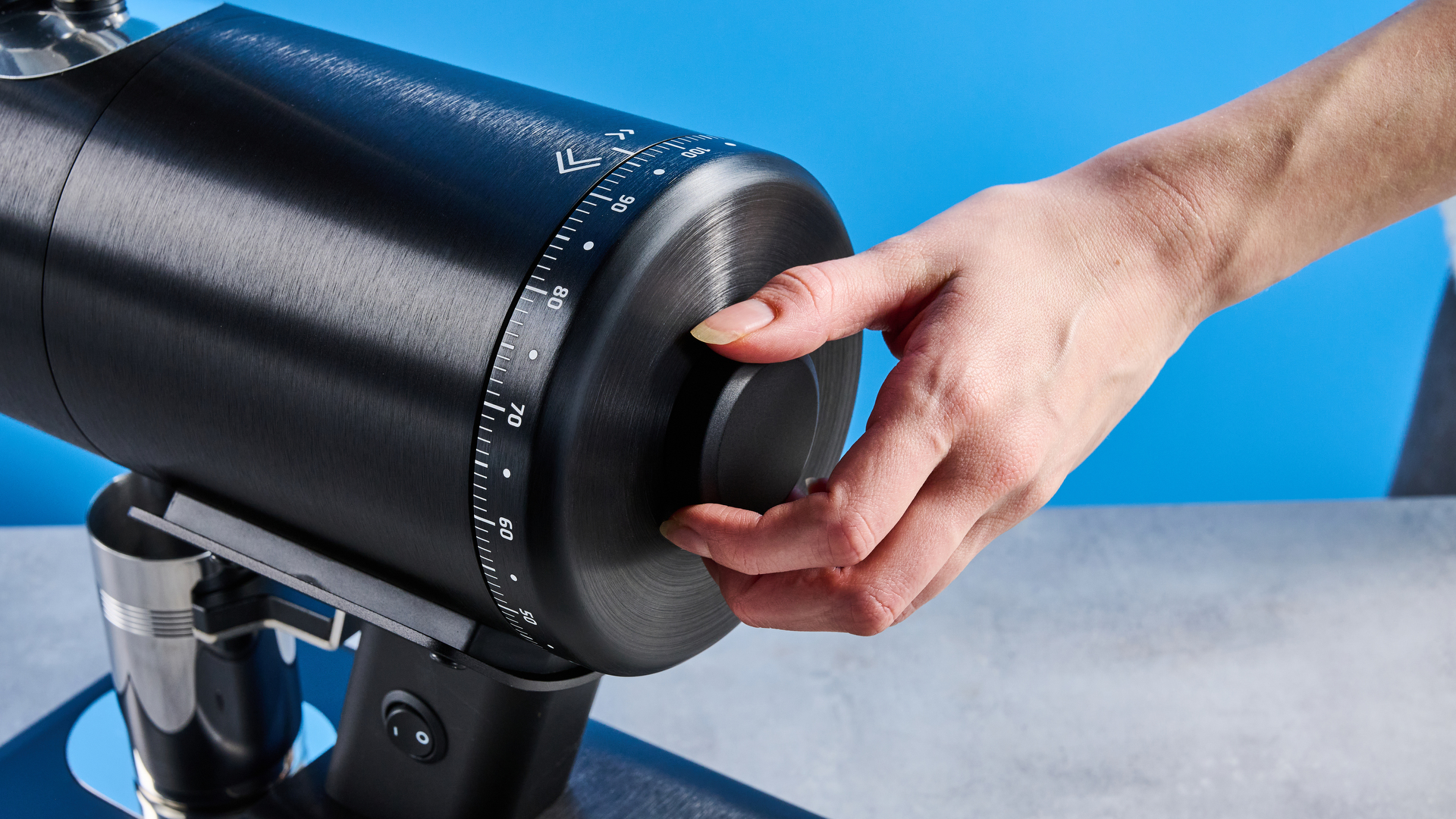 the mazzer philos coffee grinder in black and stainless steel photographed against a tom's guide blue background