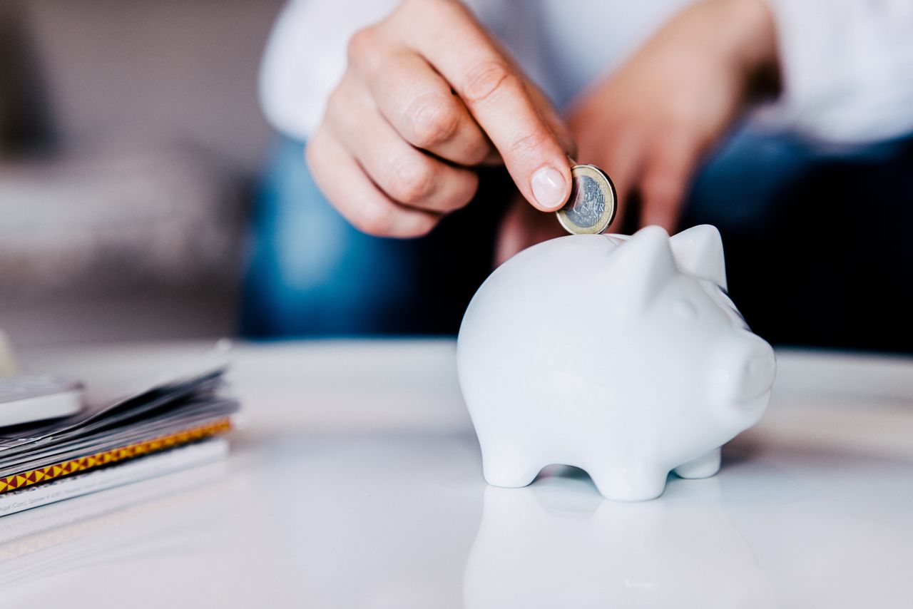 Putting a coin in a white piggy bank at home