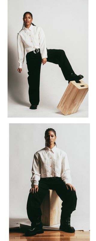 Lex Scott Davis photographed in studio wearing a cropped white button-front jacket and black trousers with black lace-up boots.