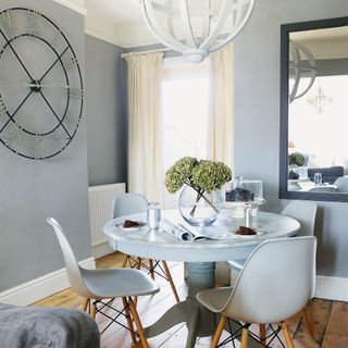 Grey dining room with round table, oversized clock and rectangular mirror