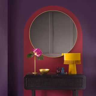 Purple bedroom with magenta painted arch in front of a black dressing table