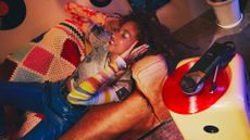 A girl wears headphones while lying on a couch and listening to a record