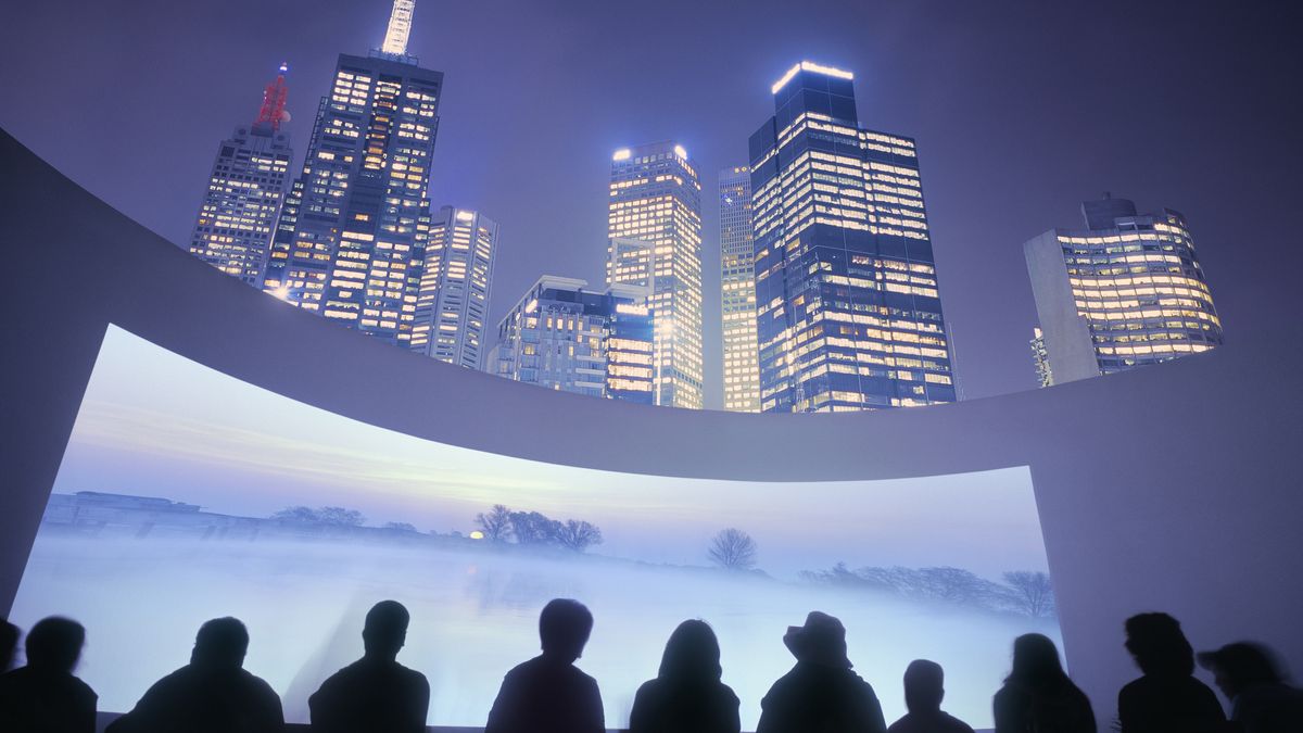 A city skyline with a projection screen below it and people marveling at it. 