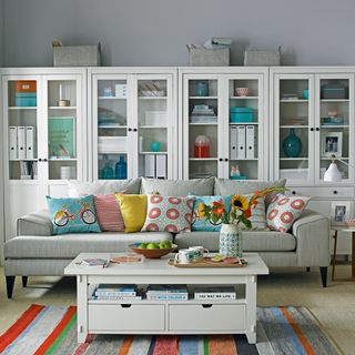 Grey living room with white storage cupboards with glass cabinets