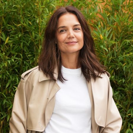 Katie Holmes at Milan Fashion Week wearing a trench coat and classic loafers
