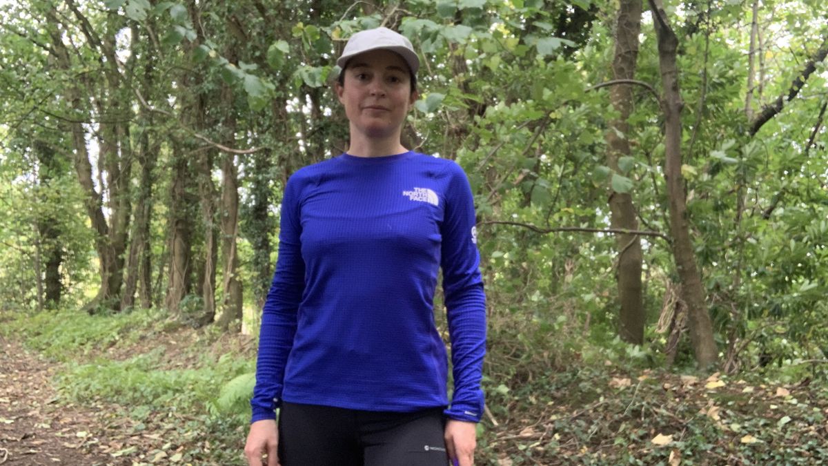 Trail runner in the woods wearing a blue top