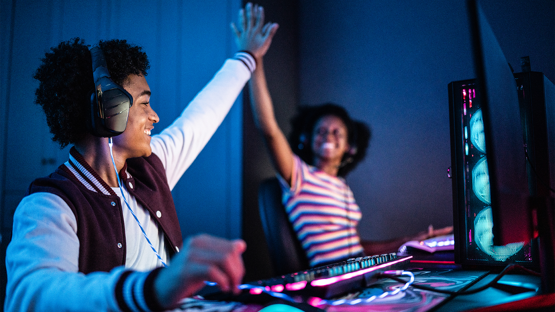 Friends doing a high five while playing on the computer at home