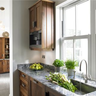 kitchen with wooden cabinets marble worktop window and open sink