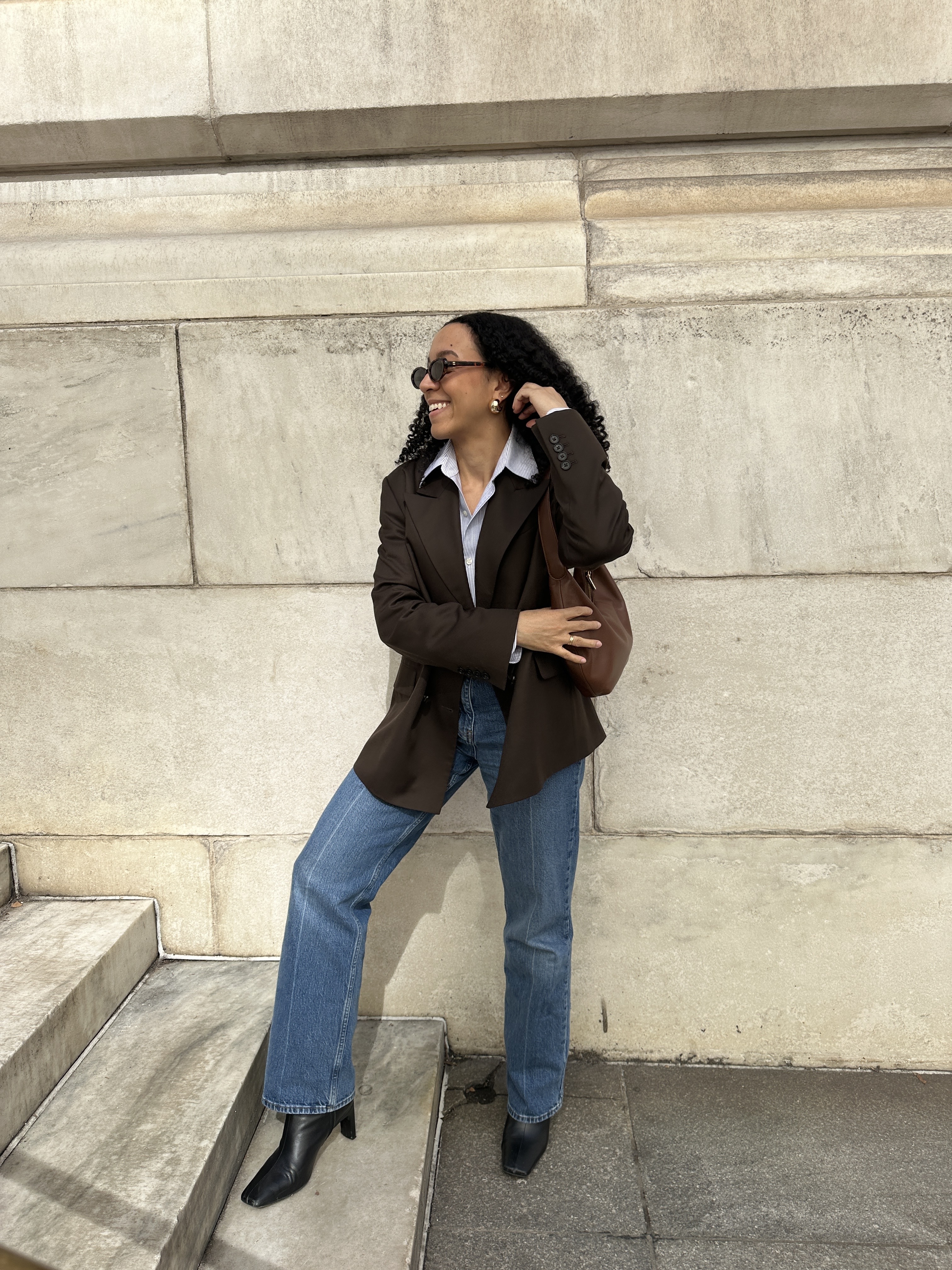 Lauren Tappan wearing a brown blazer, a button-down shirt, jeans, and black boots