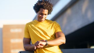 Cheerful man checking GPS watch during workout