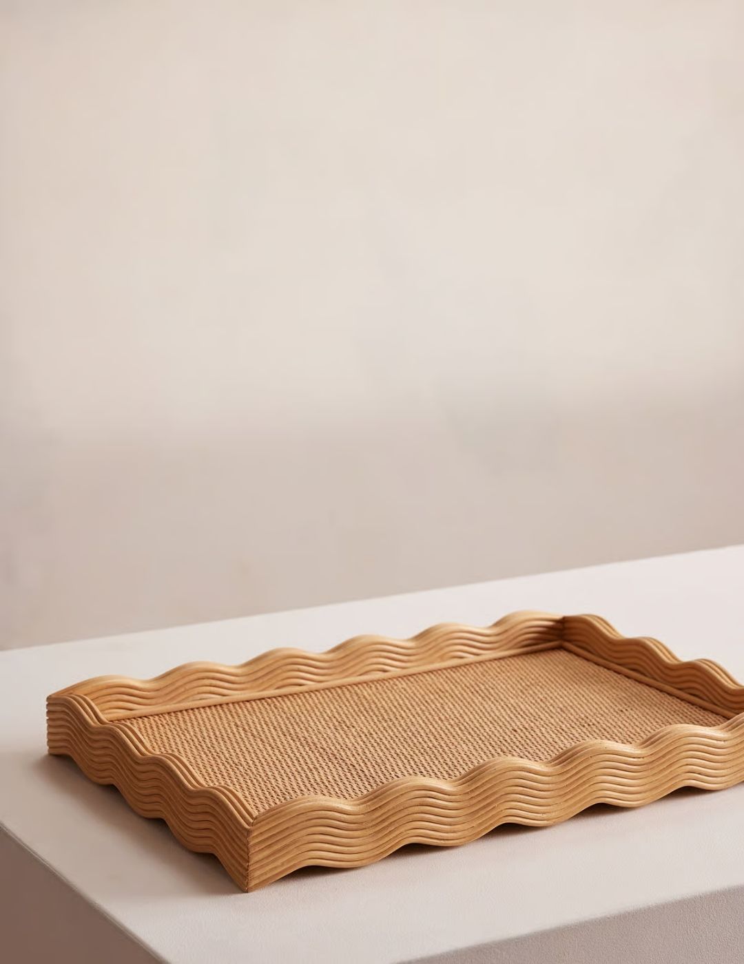 A rattan and wood tray sits atop a plain wooden shelf in white-painted wood.