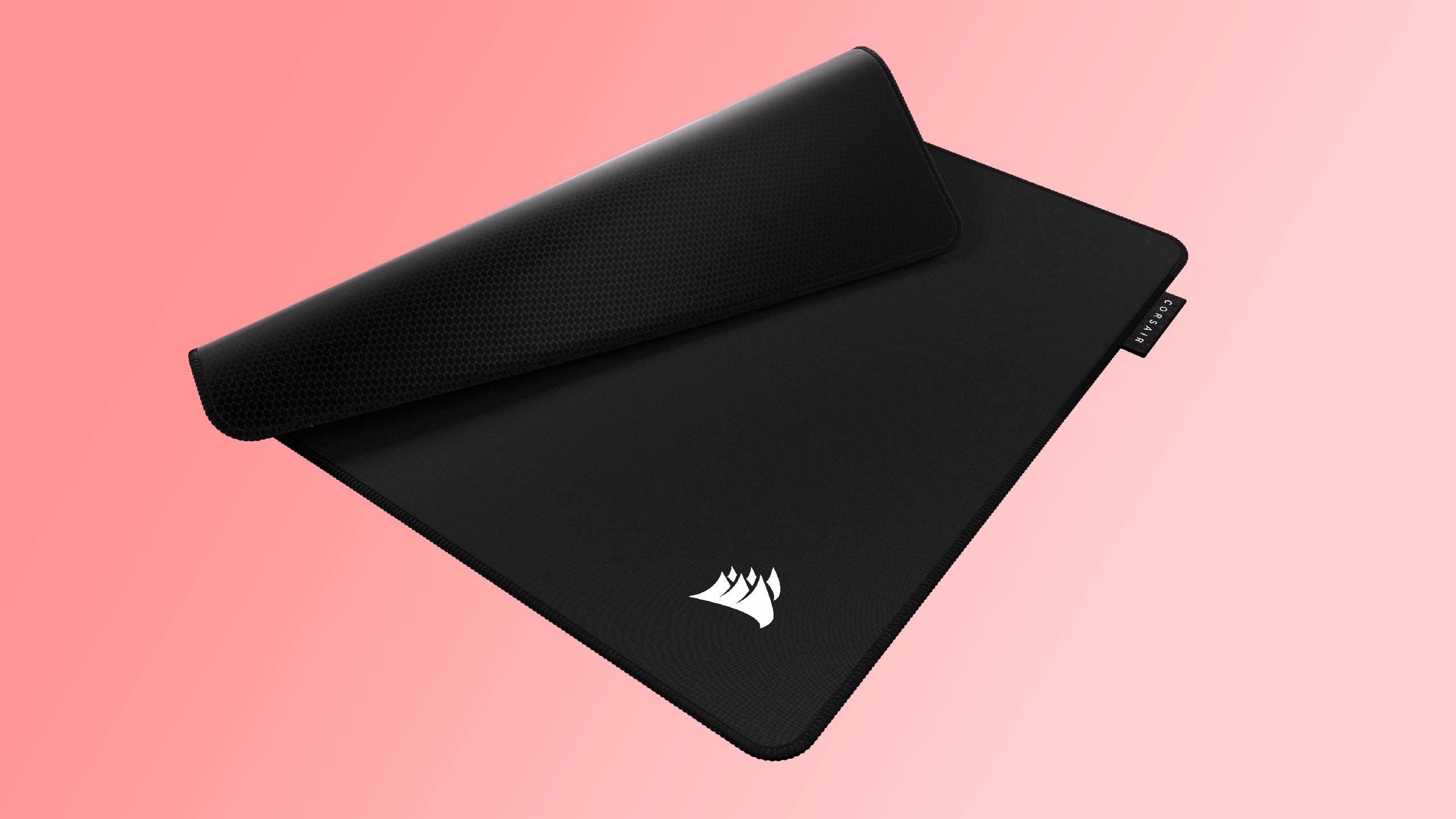 A Corsair MM Pro mouse pad on a light red and pink background.