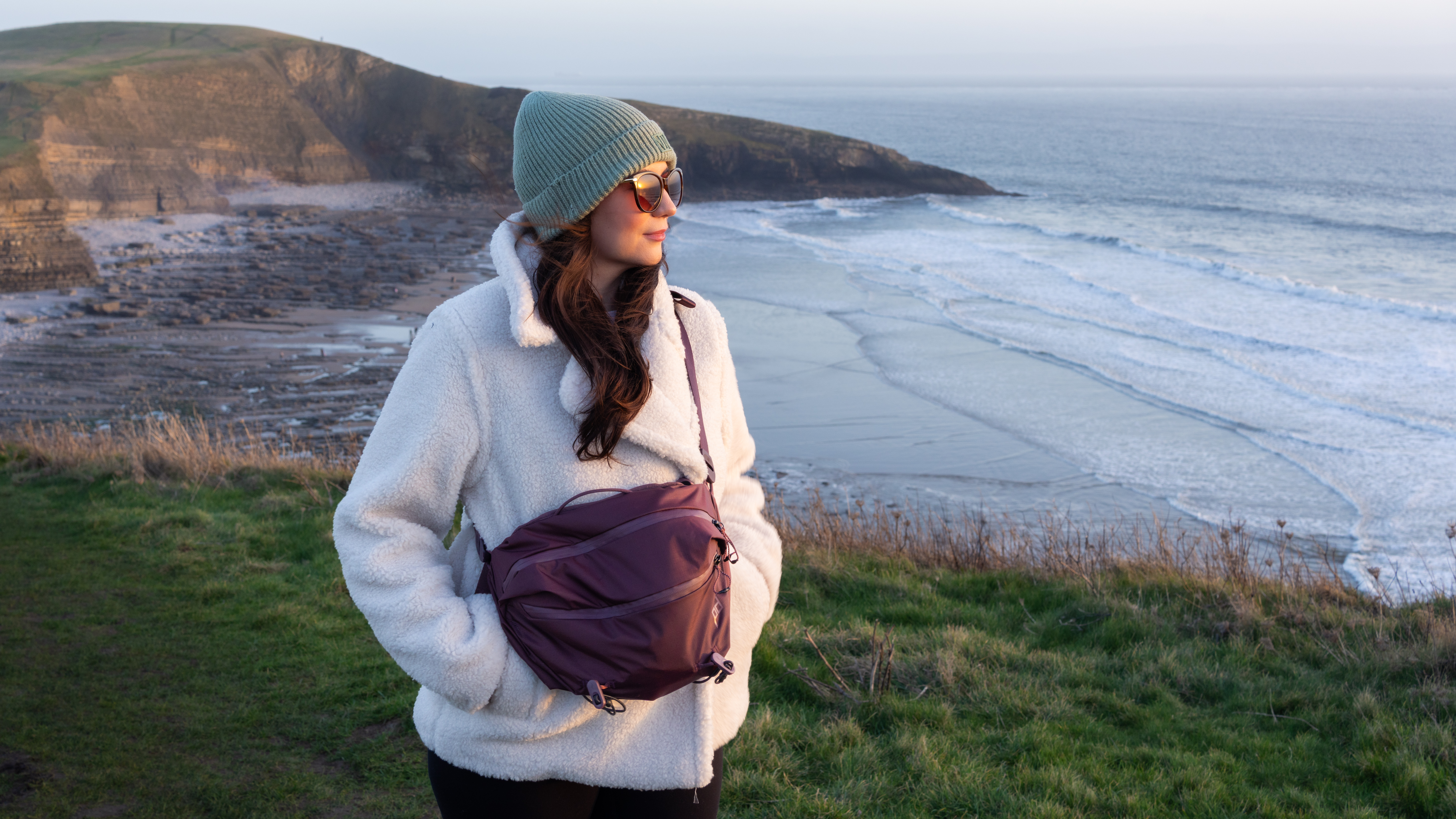 woman wearing the peak design outdoor sling bag at a coastal location