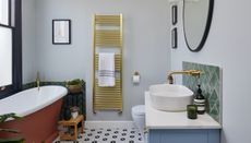 bathroom with red bath blue vanity, brass towel rail and tiled floor