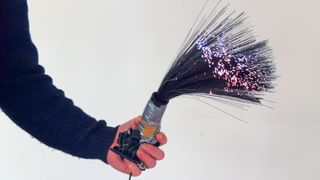 A man holding a fibre optic light painting brush with various vibrant colors at the tips of each fibre optic cable