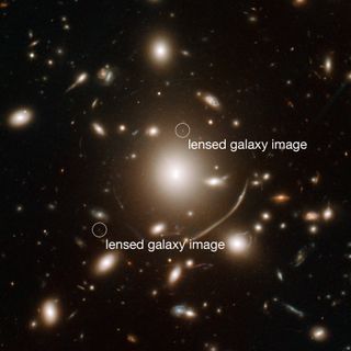 Using the galaxy cluster Abell 383 (center) as a "gravitational lens," astronomers identified a galaxy so far away we see it as it was 950 million years after the Big Bang. It is visible as two tiny dots on either side of Abell 383. Distant objects seen t
