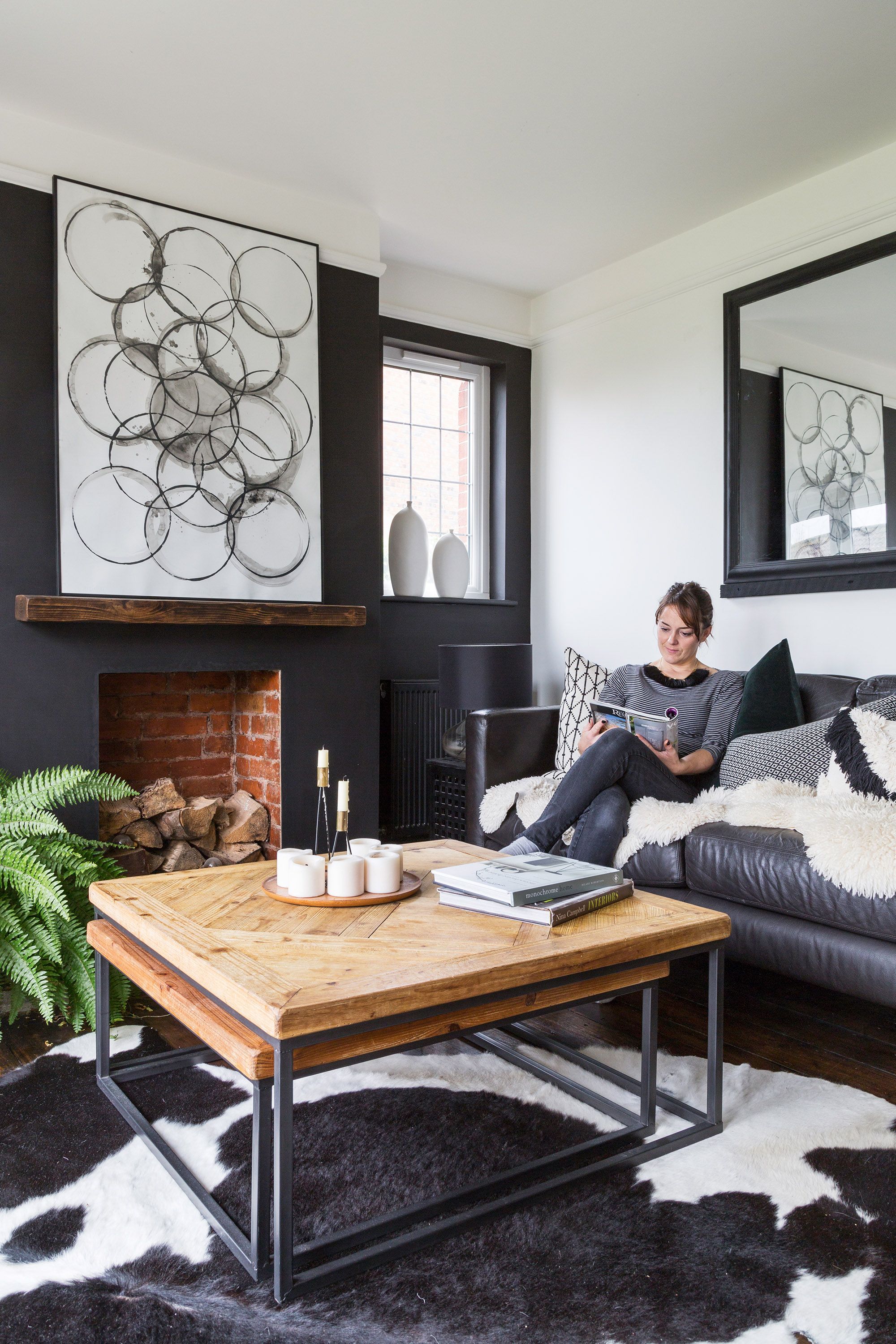 Monochrome living room with large wooden coffee table, cow print rug and leather sofa