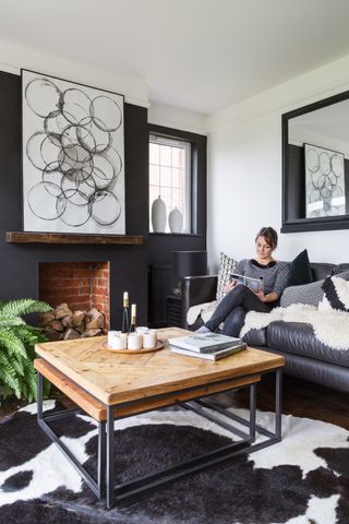 Monochrome living room with large wooden coffee table, cow hide rug and leather sofa