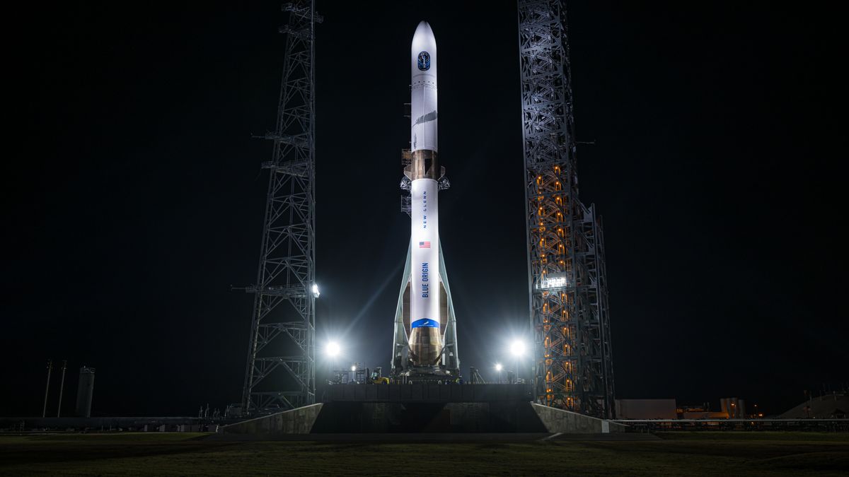 a white rocket stands on a launch pad at night