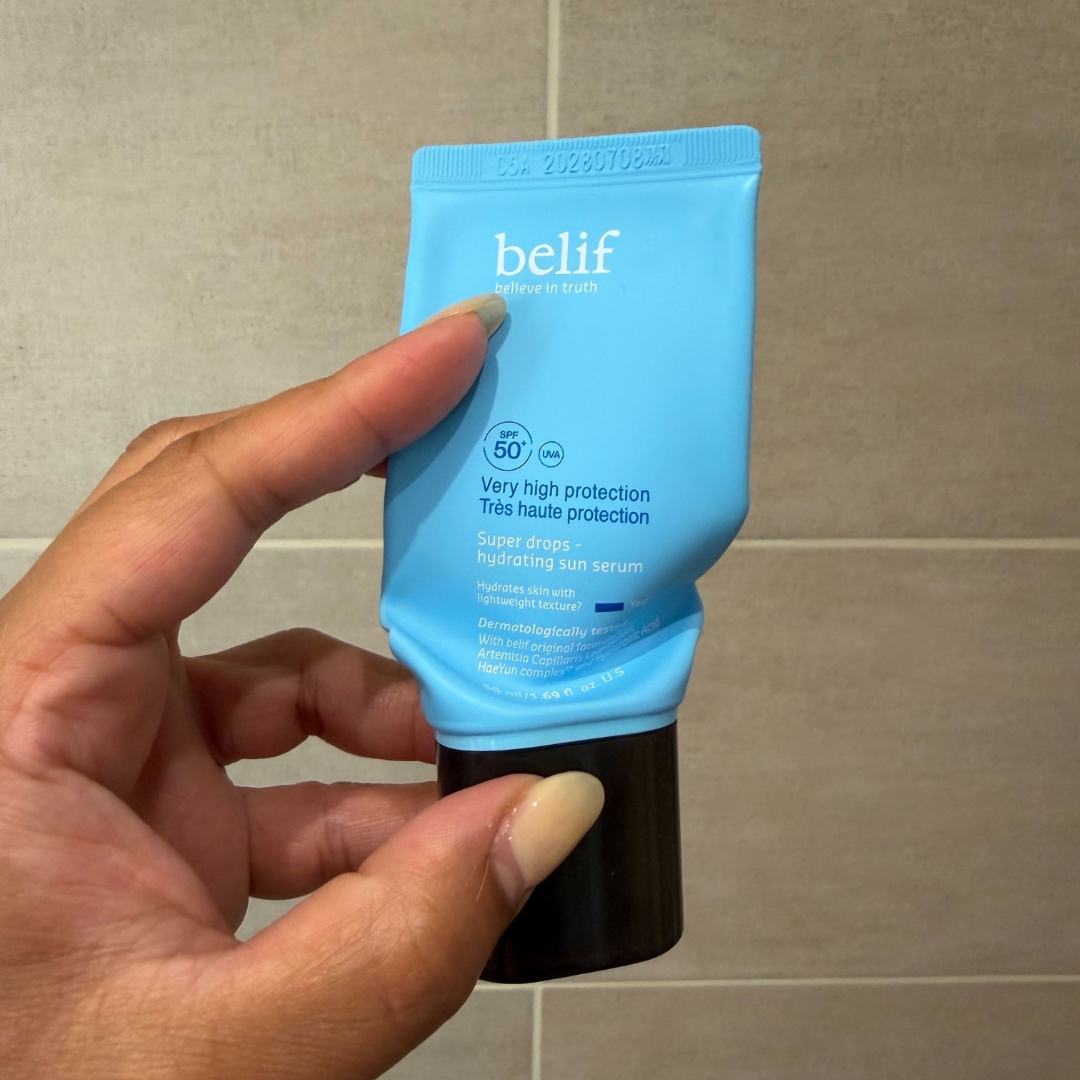 Hand holding an empty blue tube of belif Super Drops Hydrating Sun Serum SPF 50+