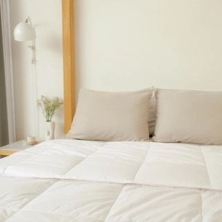 Lightweight comforter on bed with cream headboard 