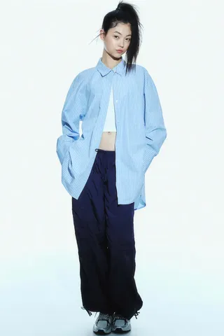 model wears Nylon Parachute Pants and blue striped button down