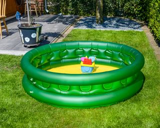 A paddling pool in a small backyard with lawn