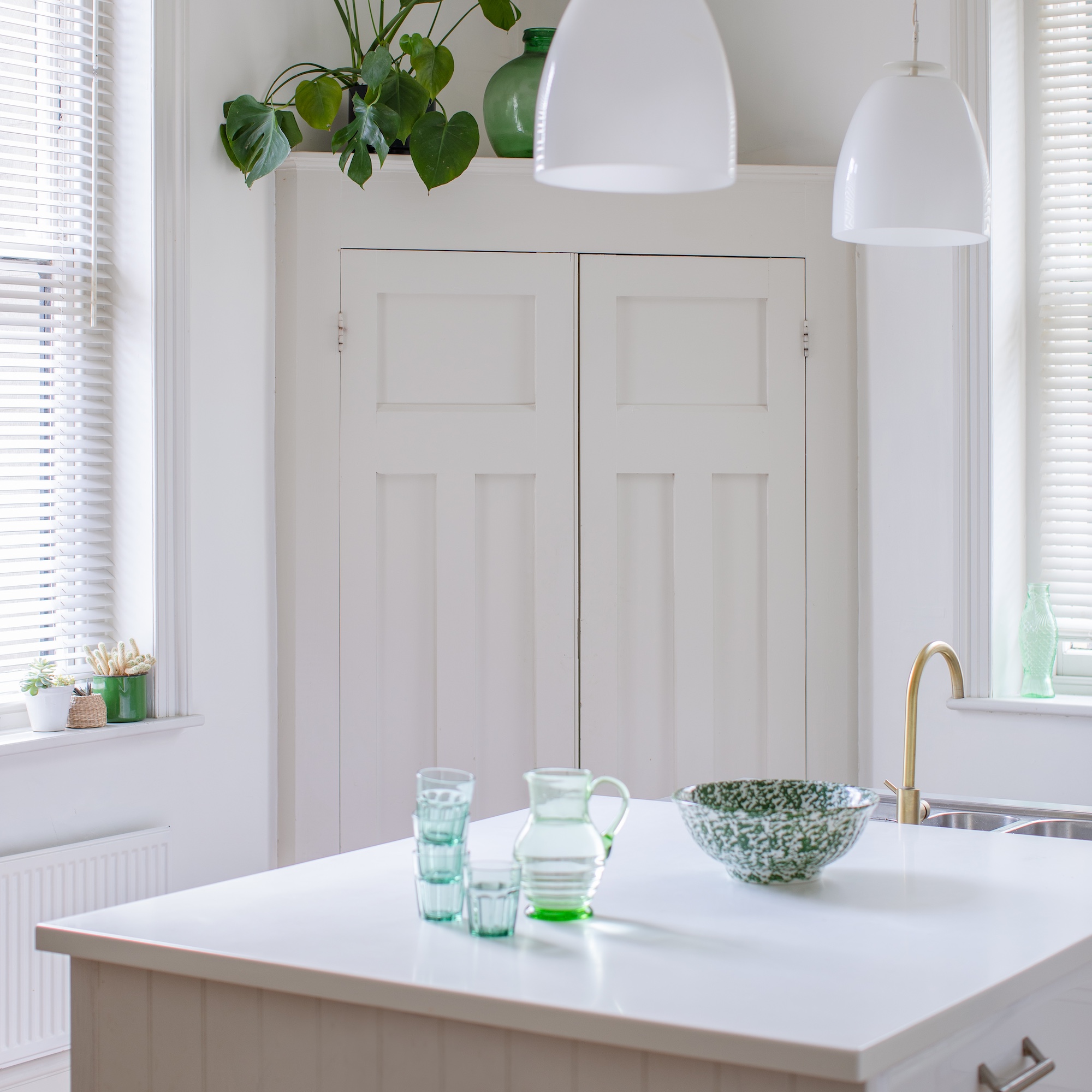 kitchen with large white corner cupboard and white island with white countertop and two pendant lights above