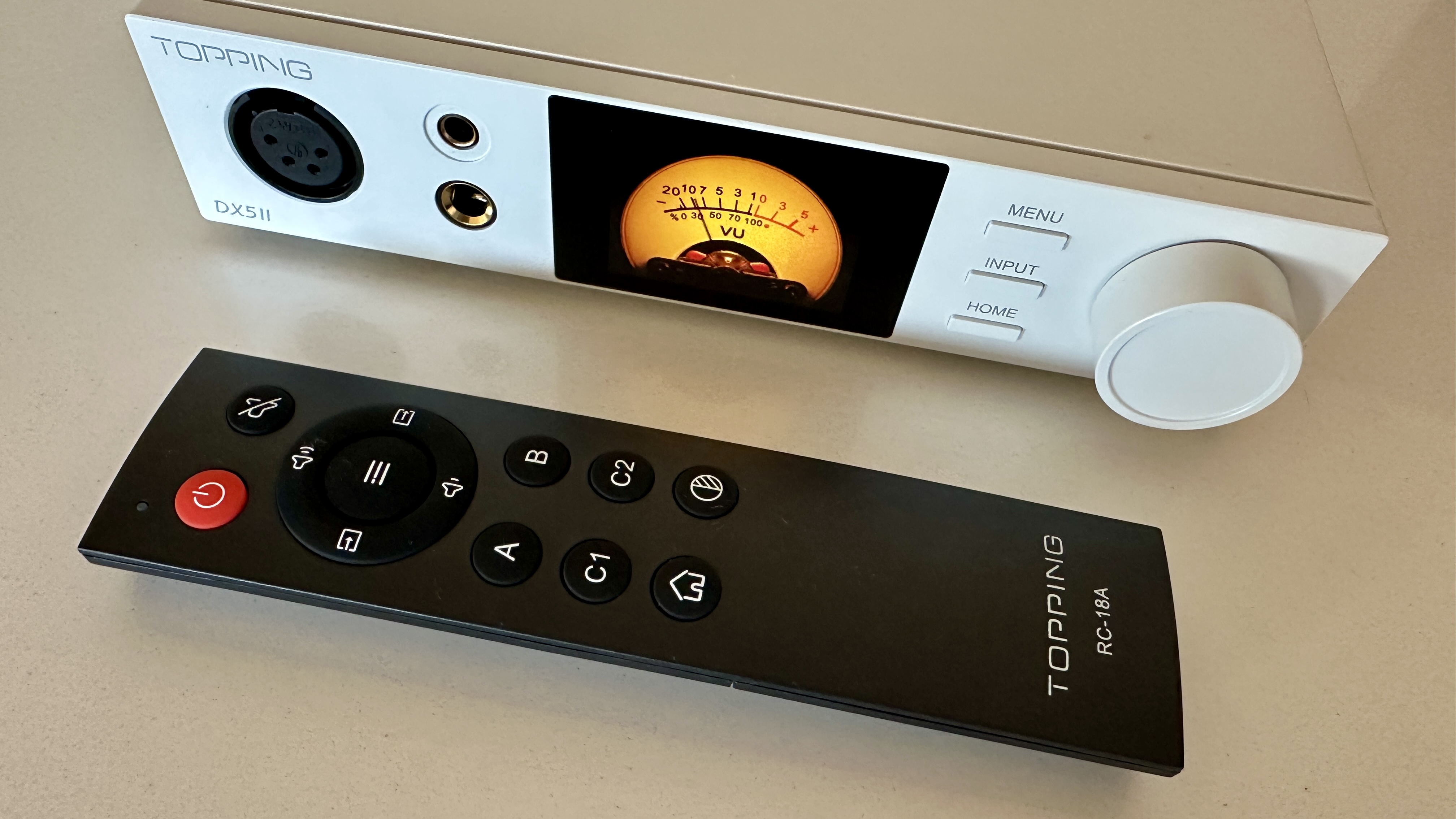 The Topping DX5 II on a light-wood table, showing the VU meter, ports and just-seen remote