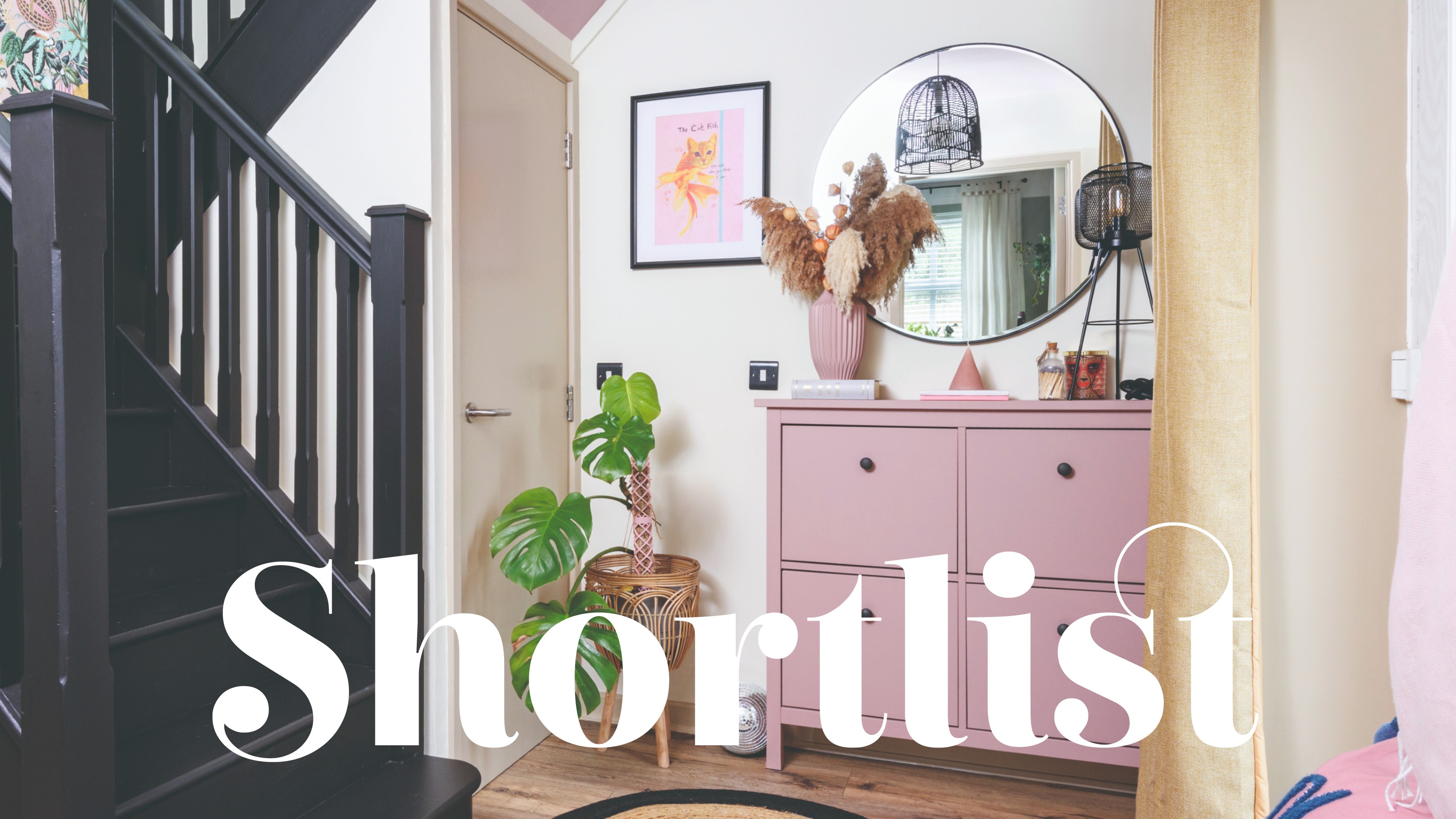 A white hallway with a pink shoe storage cabinet and a round wall mirror hung above it