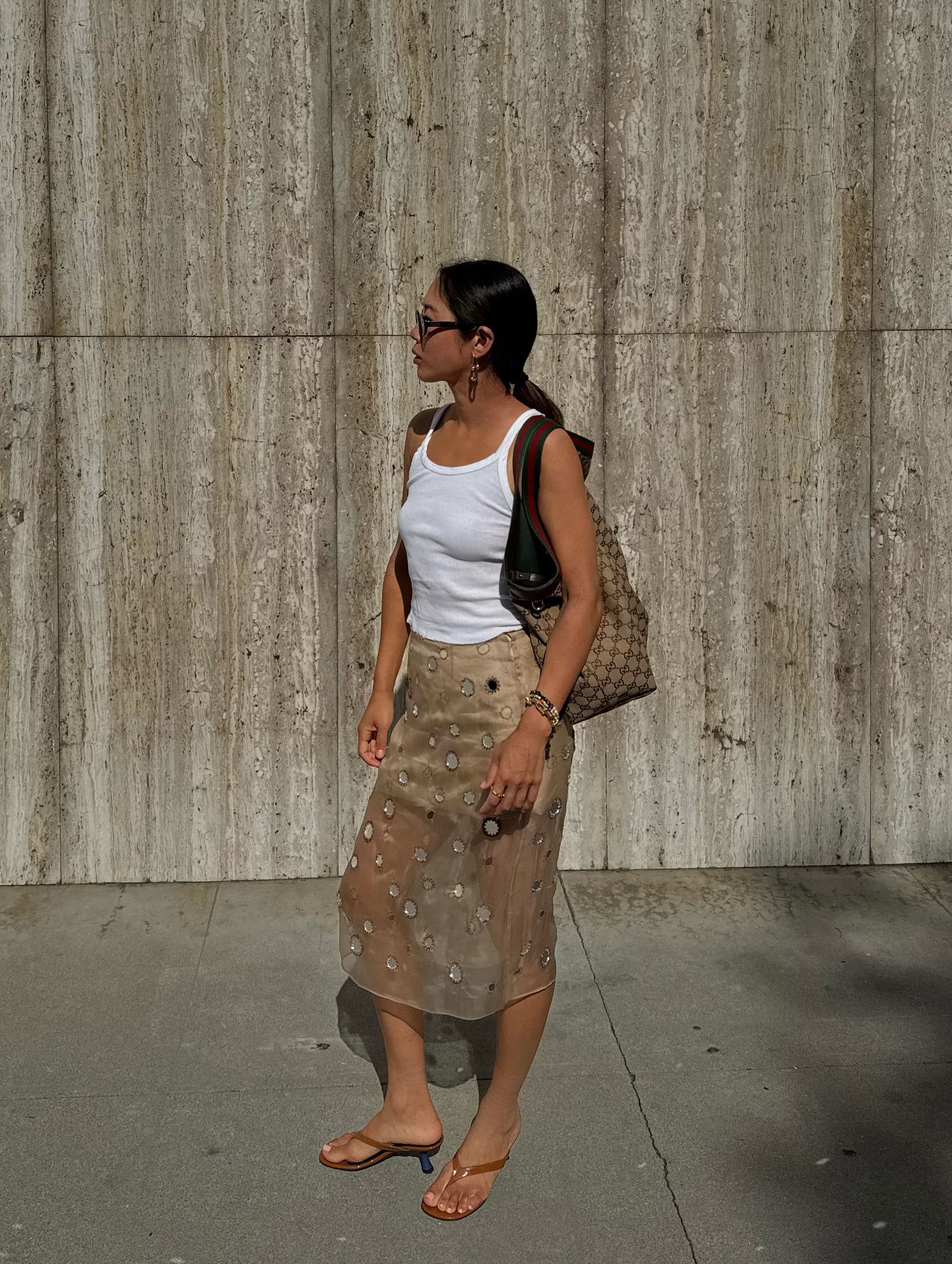 Aimee Song wears a white tank top and sheer mirror skirt