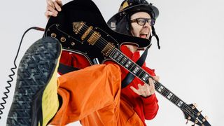 Paul Gilbert wears a fireman suit as he takes his new signature Ibanez FRM350 for a spin