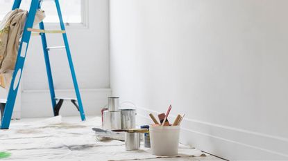 A painting kit and stepladder by a blank white wall