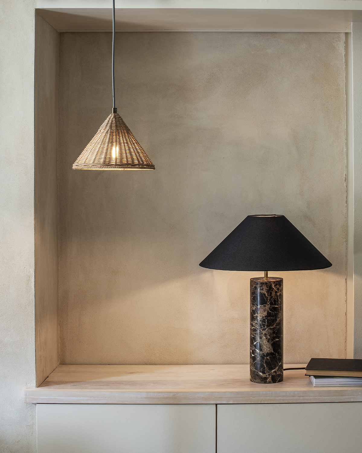 black marble table light and rattan shade against a limewash wall