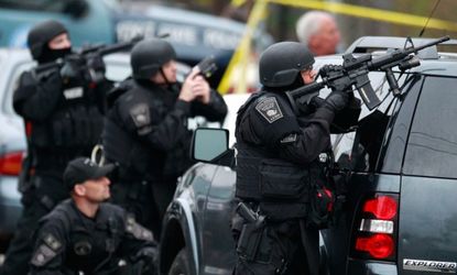 Police in tactical gear surround an apartment building in Watertown, Mass., April 19.