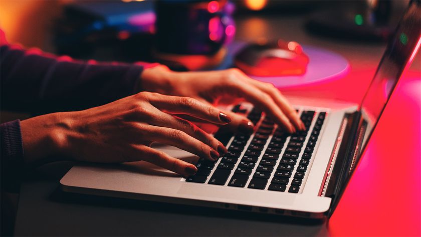 Person typing on a laptop in a low lit room