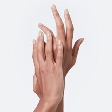 Hands with gucci 212​ Annabel Rose nail polish on light grey background
