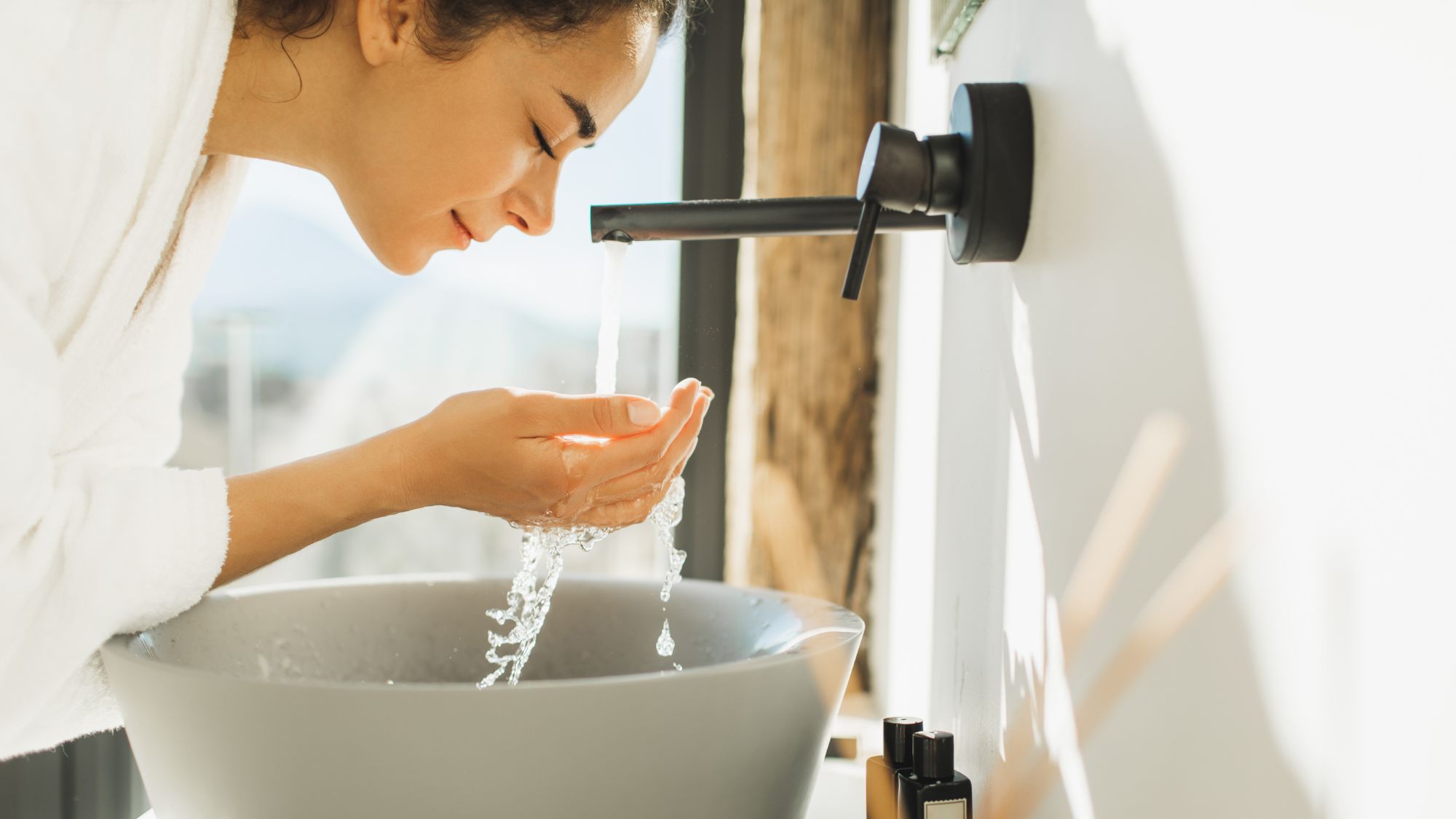 woman washing her face over a sink