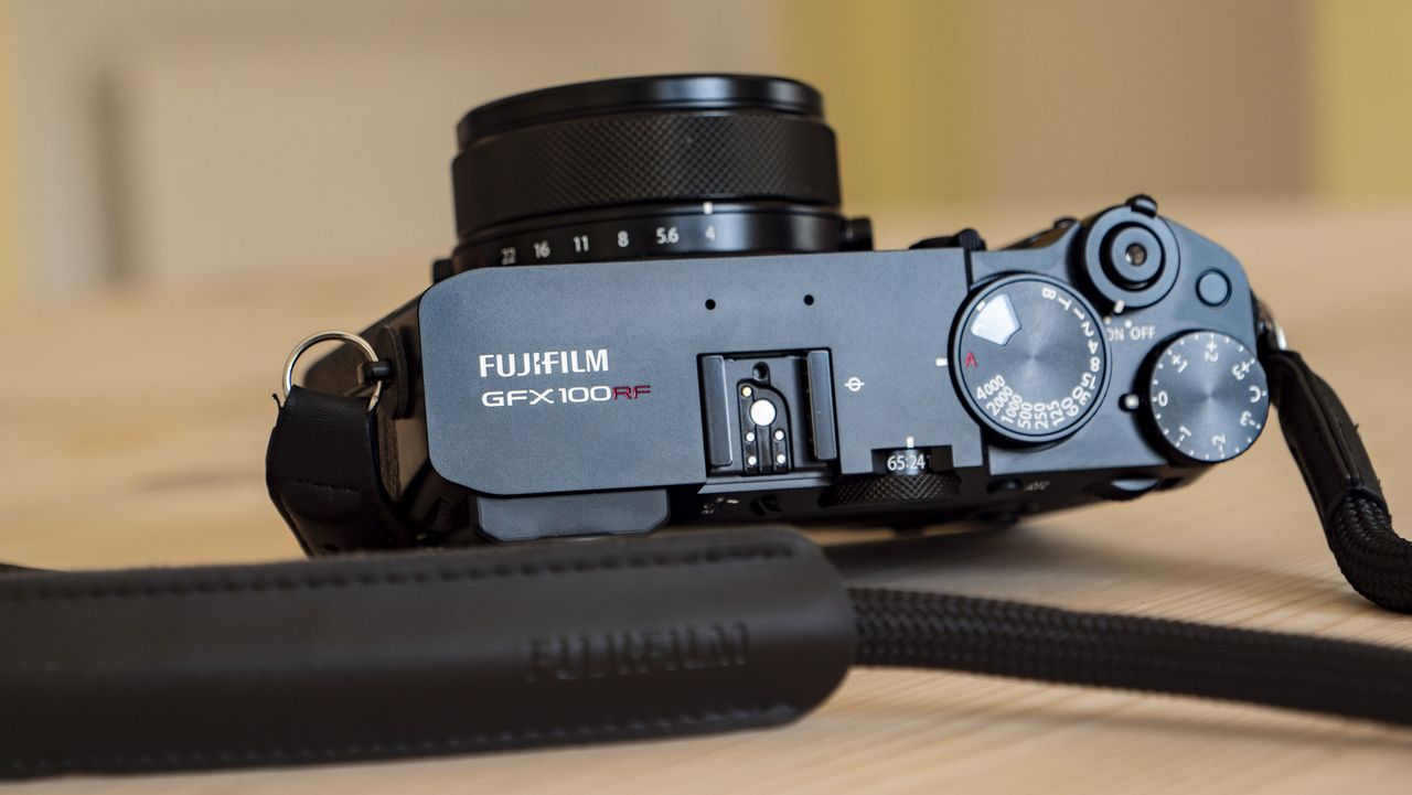 All-black Fujifilm GFX100RF rangefinder-style camera on a wooden table