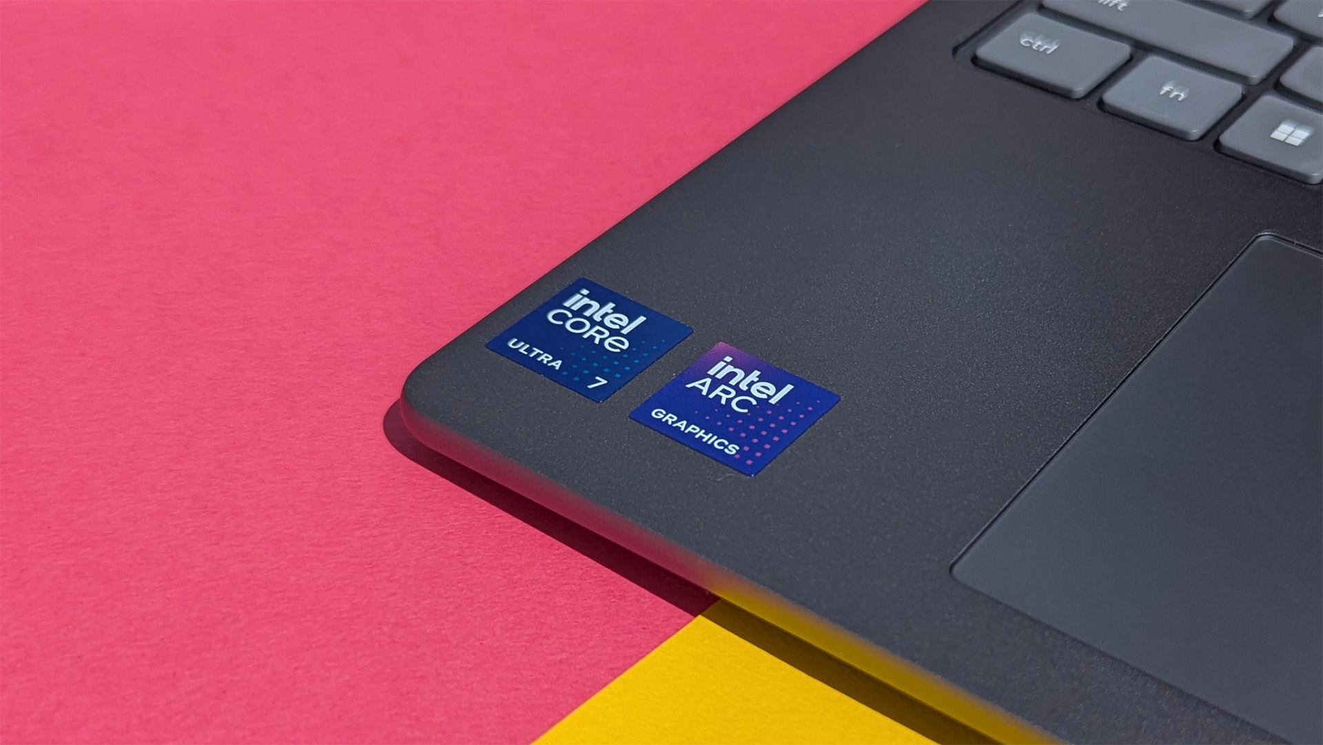 Lenovo Yoga 7i 16 (Gen 10) laptop with Intel Core Ultra 7 and Intel Arc graphics stickers on pink and yellow card.