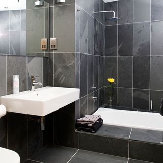 wet room with grey slate wall and white basin