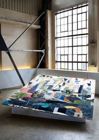 A painting printed onto a carpet on a raised platform with a large window behind it.