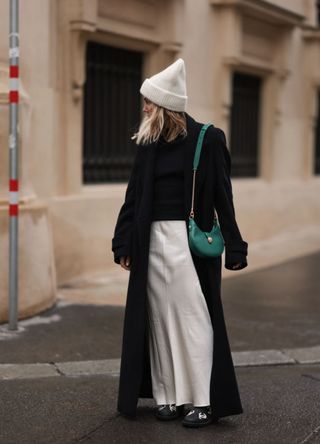 A woman wearing a white shirt with a long black trench coat