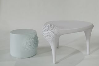 A round, light blue side table is to the left, and a white rounded triangle side table with three legs is to the right.
