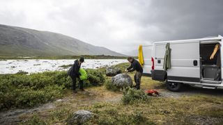 Two men set up camp in stormy conditions