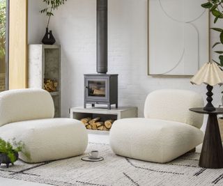 modern living room with two white comfy armchairs and freestanding log burner on log storage