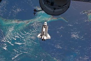 Space shuttle Atlantis approaches the International Space Station with its cargo bay doors open during STS-135, the final shuttle mission, in 2011.