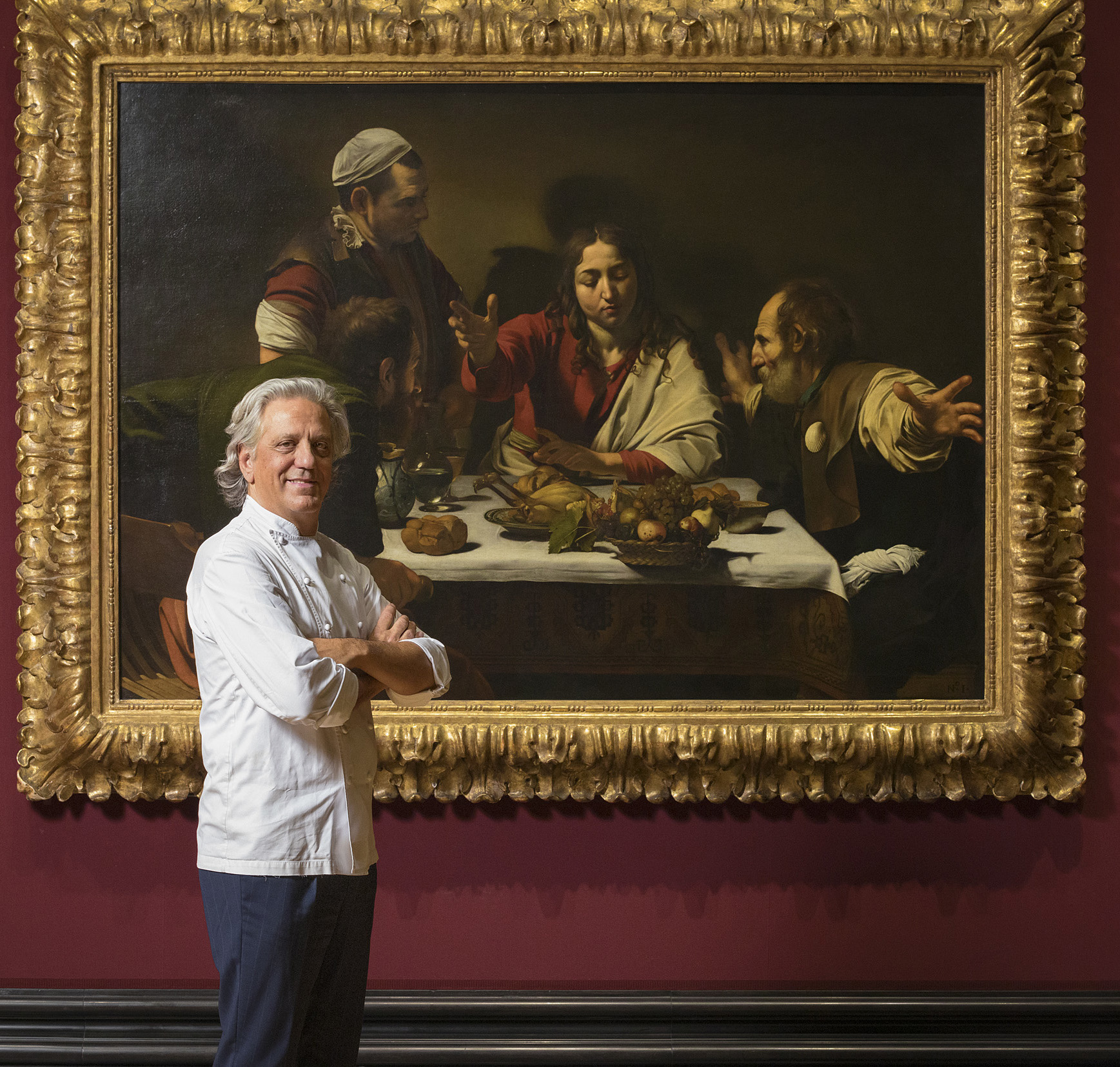 Man in chef&#039;s whites standing infront of a large painting