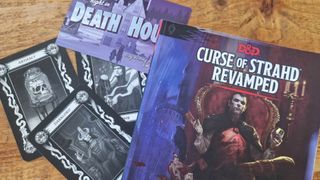 Curse of Strahd Revamped sourcebook alongside Tarokka Cards and a postcard for Death House, all on a wooden table